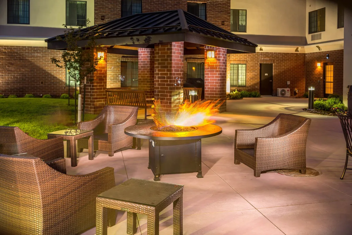 An inviting exterior BBQ area featuring a fire pit, comfortable outdoor seating, and lush landscaping. The setting is ideal for social gatherings, grilling, and relaxing evenings under the stars.